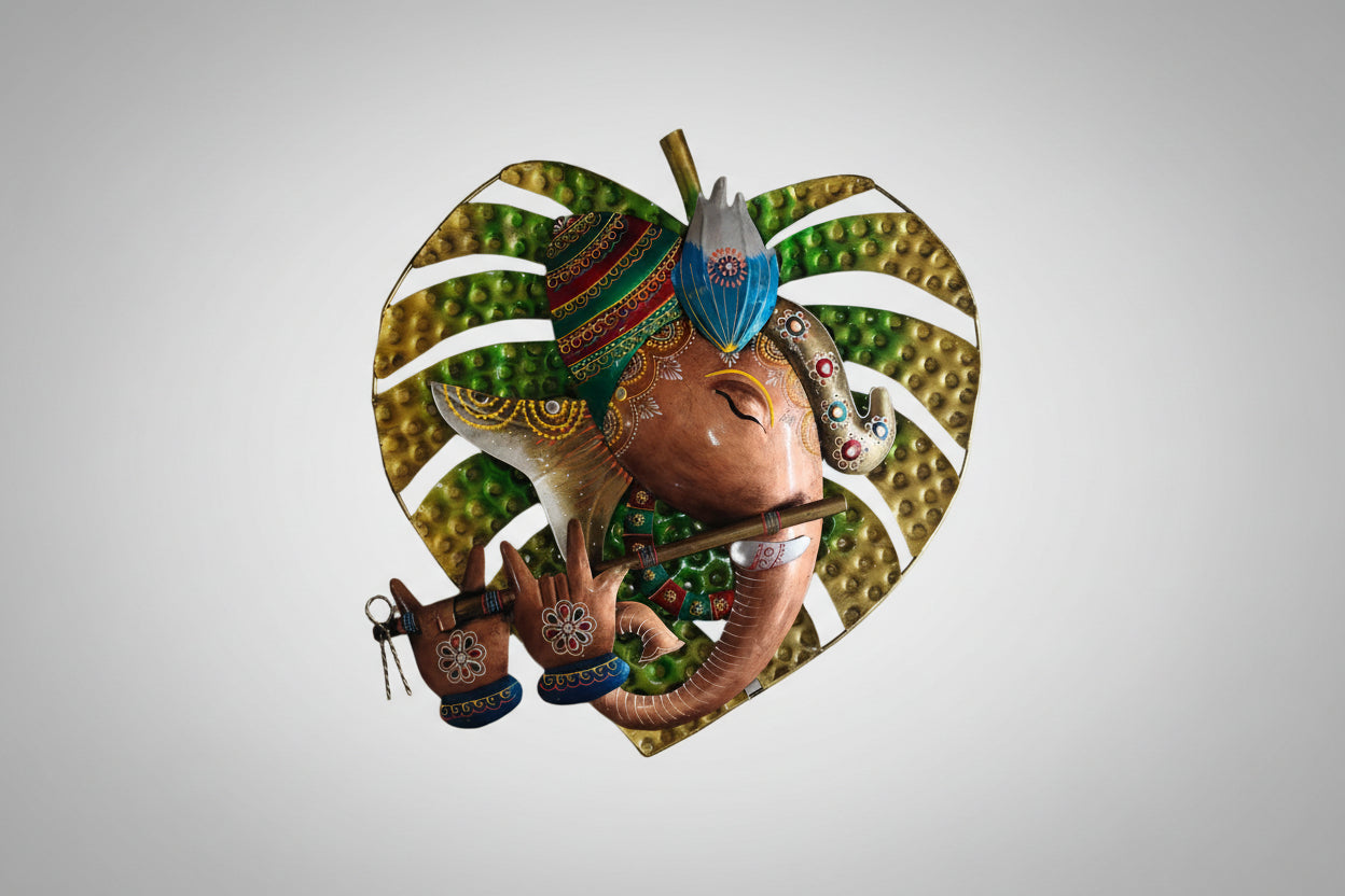 A metal wall decor featuring an artistic depiction of the elephant-god Ganesha with decorative elements and a heart shape in the background.