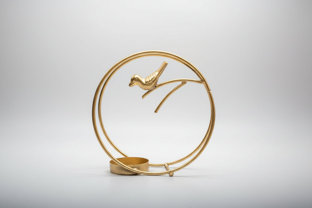 Decorative gold sculpture of a bird on a branch with a circular base.