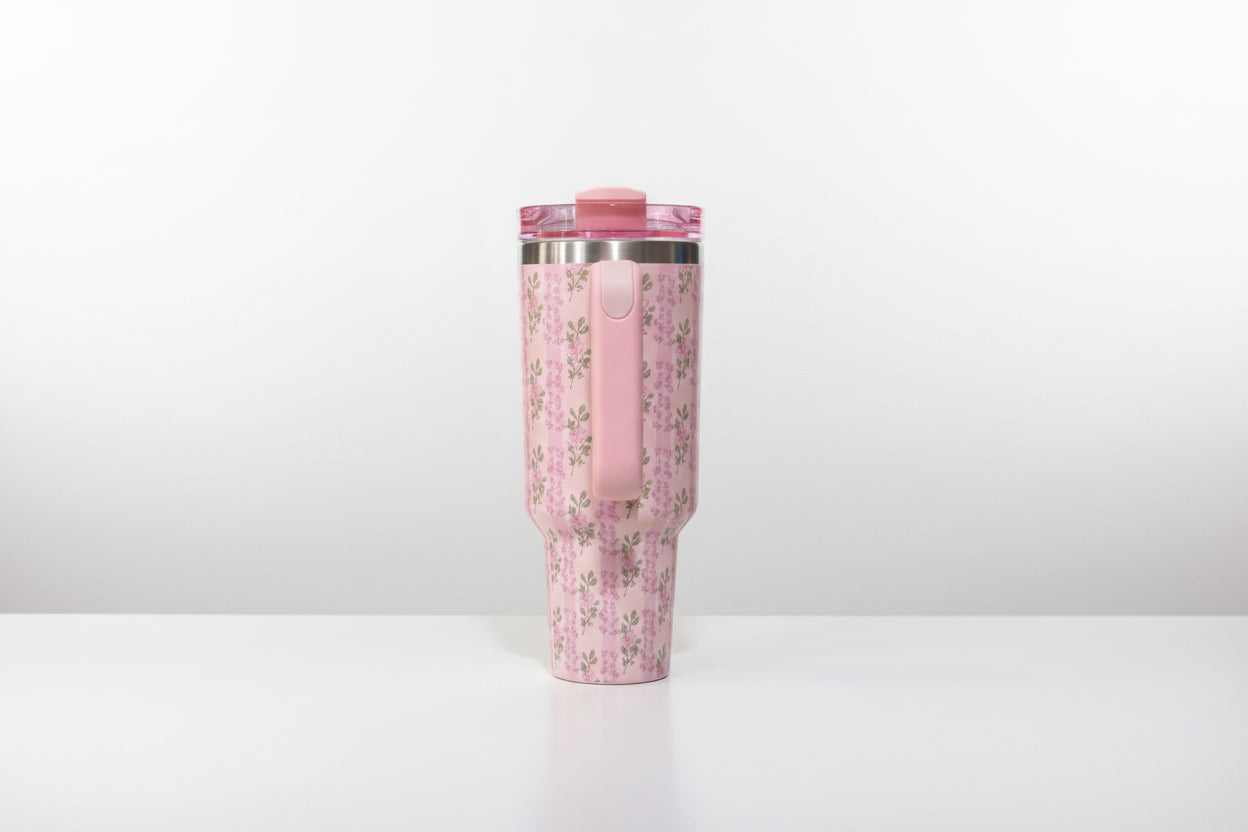 Pink tumbler with floral pattern on a white background