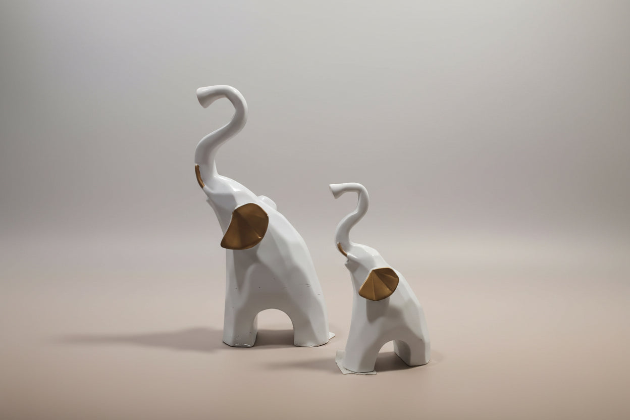 Two white elephant figurines with brown trunks on a light gray background