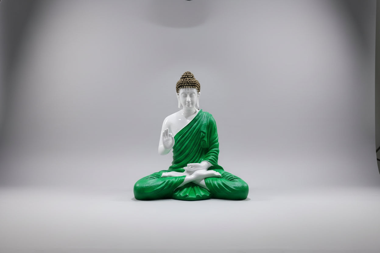 Statue of a meditating Buddha in green robes on a white background
