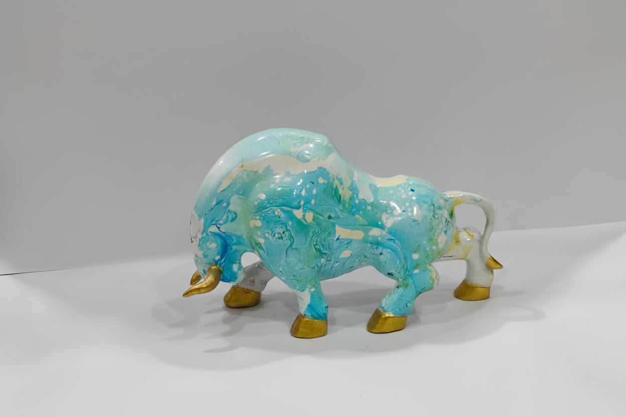 Glass buffalo figurine with blue and gold colors on a white background