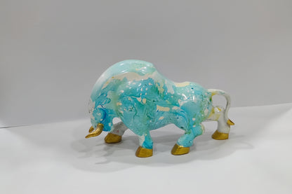 Glass buffalo figurine with blue and gold colors on a white background