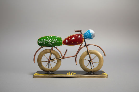 A decorative metal bike table top with a bronze frame, green seat, and blue handlebars on a white background.