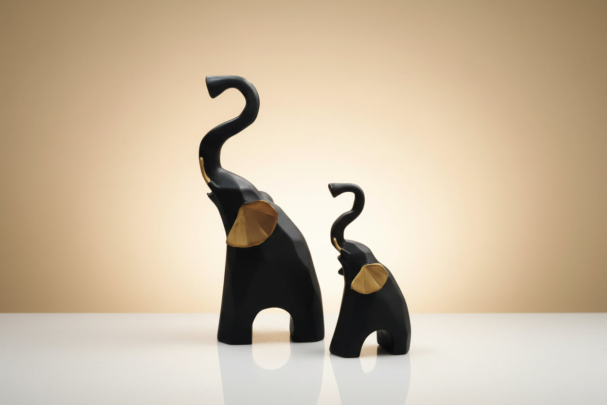 Two black elephant sculptures with gold accents on a white background