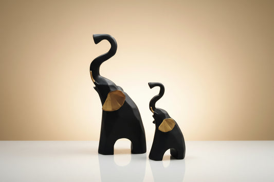 Two black elephant sculptures with gold accents on a white background