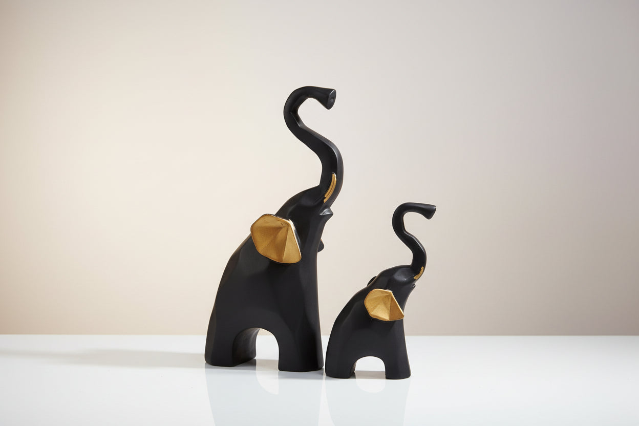 Two black elephant figurines with curved trunks on a white background