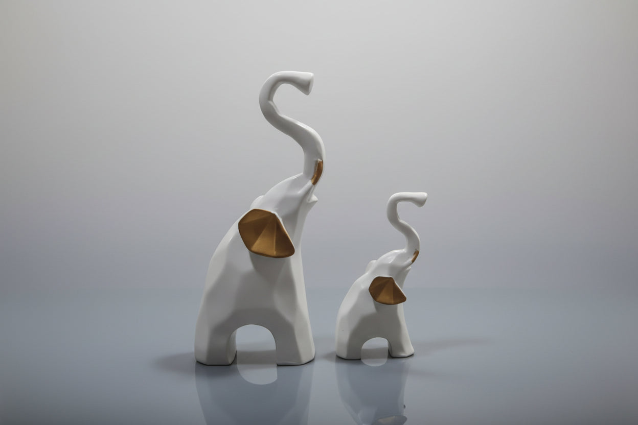 Two white elephant figurines with curved trunks on a light gray background