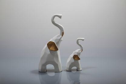 Two white elephant figurines with curved trunks on a light gray background