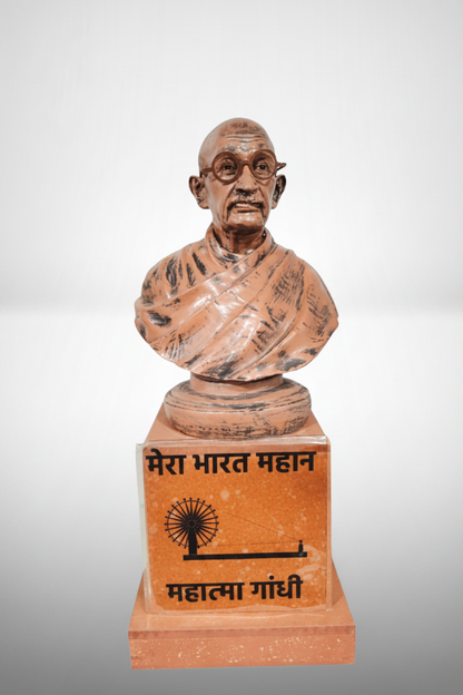 A resin showpiece statue of Mahatma Gandhi with a beige and dark brown finish, standing on a base with a plaque in Devanagari script.