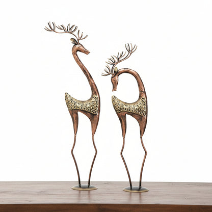 Two decorative deer figures with multicolored finish, placed on a table.