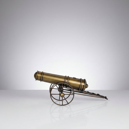 A bronze-colored metal showpiece designed to resemble an iron cannon with wheels and a barrel, mounted on a spherical base.