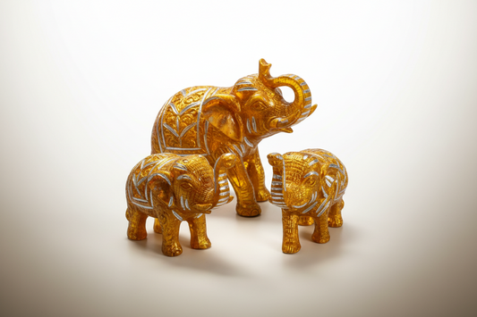 Three gold color metal elephant figurines with decorative patterns on a white background