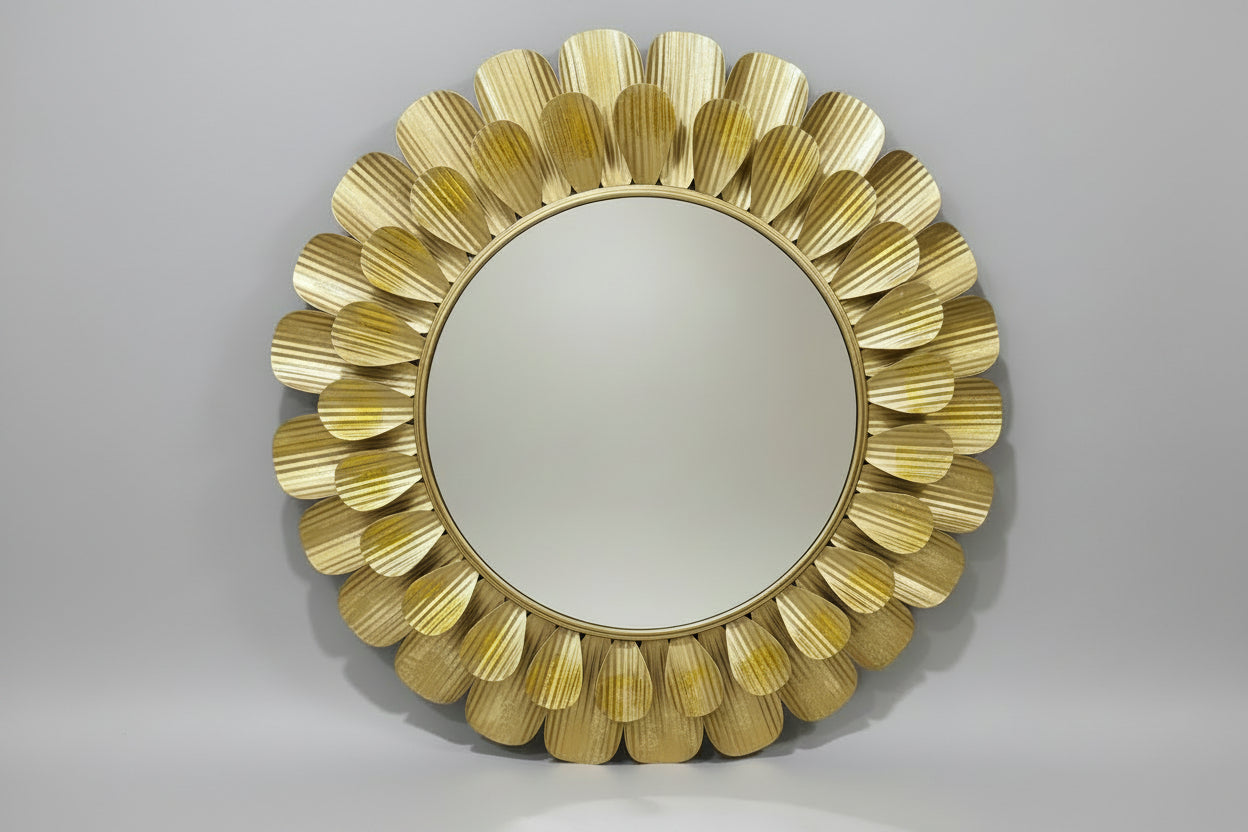 A decorative metal mirror wall décor with a gold color and leaf-like patterns around the frame, displayed in a store setting.