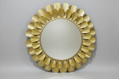 A decorative metal mirror wall décor with a gold color and leaf-like patterns around the frame, displayed in a store setting.