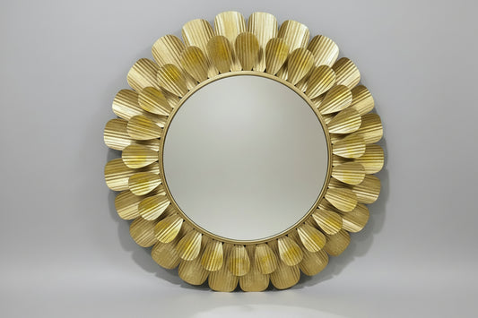 A decorative metal mirror wall décor with a gold color and leaf-like patterns around the frame, displayed in a store setting.