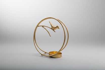 Decorative gold sculpture of a bird on a branch with a circular design