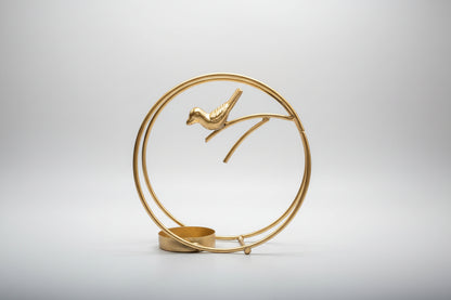 Decorative gold sculpture of a bird on a branch with a circular base.