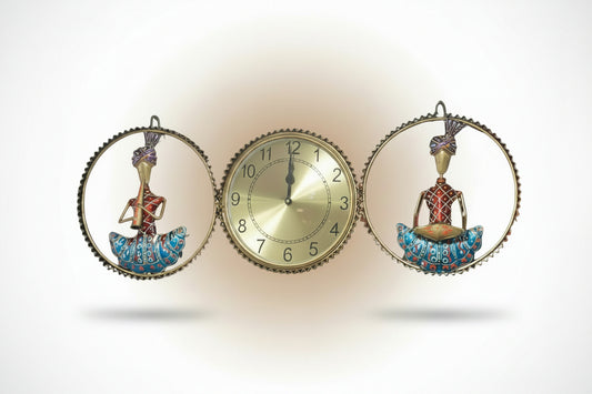 A metal wall clock decor featuring a central clock with a golden clock face, surrounded by two decorative figures in blue and red.