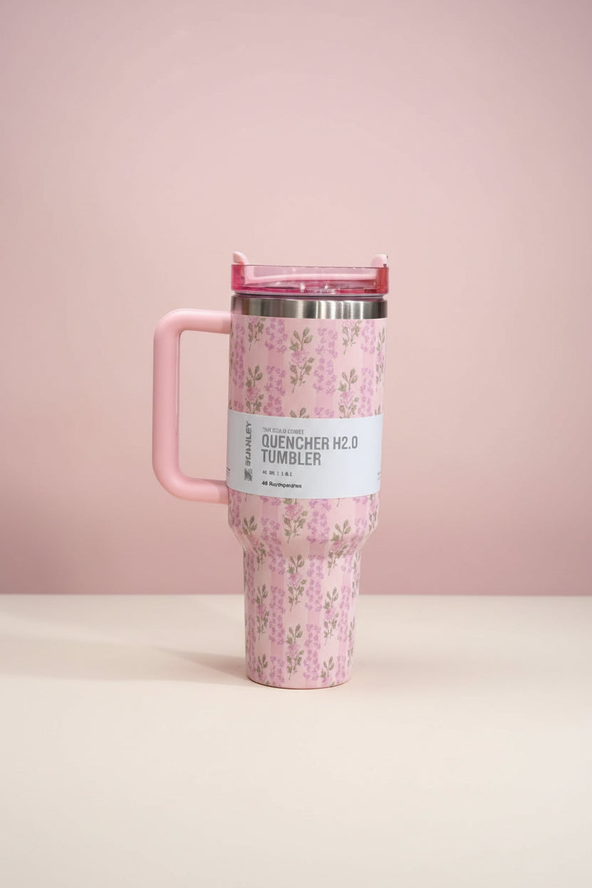 Pink floral travel mug with a handle on a white background