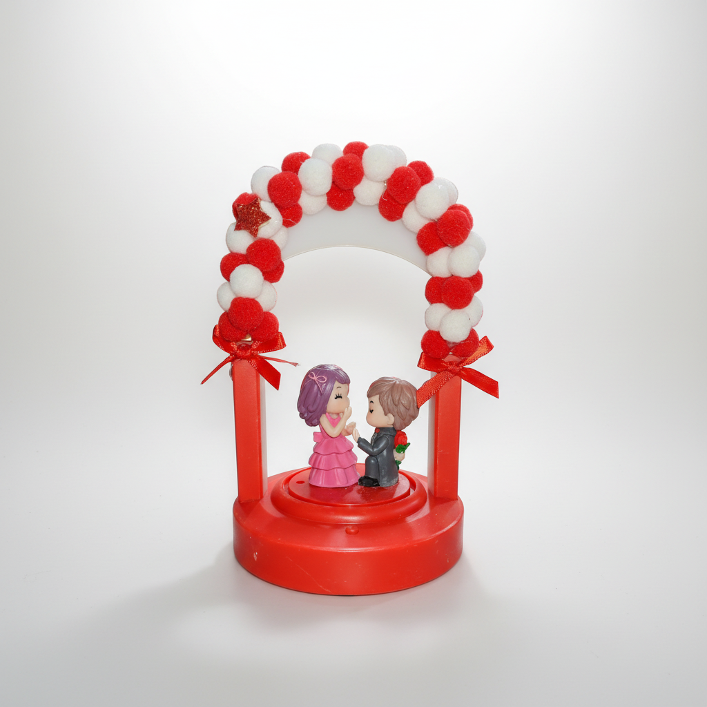 A decorative showpiece featuring a couple figurine standing under a red and white arch with ribbons and pom-poms.