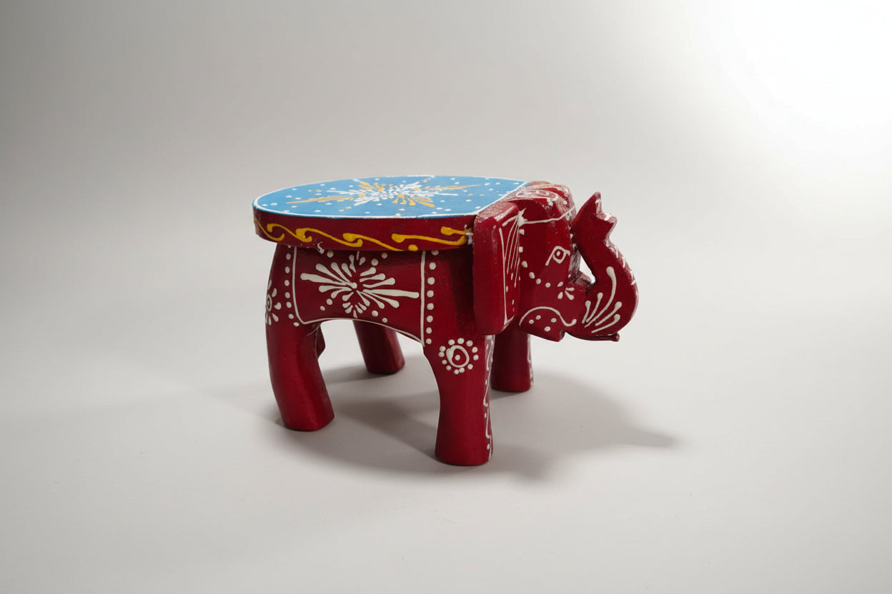 A handcrafted wooden elephant stool with red and blue colors and intricate details.