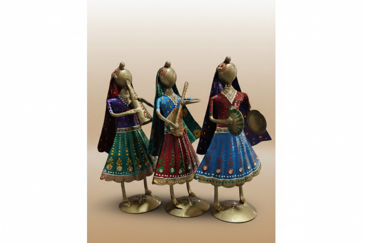 A set of three metal musician small dolls in various colored traditional attire, positioned on a tabletop.