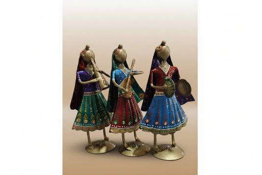 A set of three metal musician small dolls in various colored traditional attire, positioned on a tabletop.